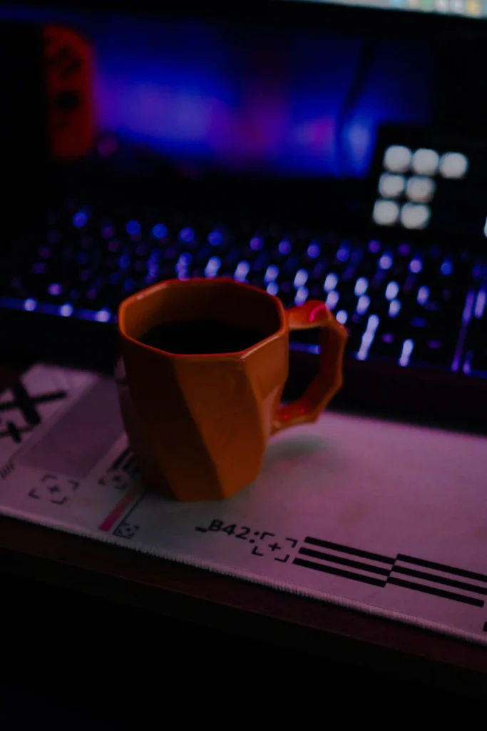 Taza de café sobre escritorio oscuro con teclado retroiluminado de fondo que ilustra la sección de precio del taller Ask Expert.